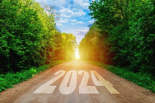 New year 2024 or straightforward concept. Text 2024 written on the road in the middle of empty road at sunset.Concept of planning and challenge, business strategy, opportunity ,hope, new life change.