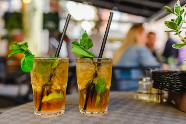 Alkol içeceği. Dışarıdaki Masa Kafe 'de. Alkollü bardaklar ve yarım limonlu, nane yapraklı. Limonlu kokteyl mojito ve nane yaprağı. Şehir hayatı. Kafenin arka planı bulanık. İyi akşamlar..