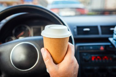 Ulaşım ve araç trafiği sıkışıklığı kavramı. Trafik sıkışıklığında sabah araba kullanırken elinde kağıt bardak sıcak kahve içen biri..