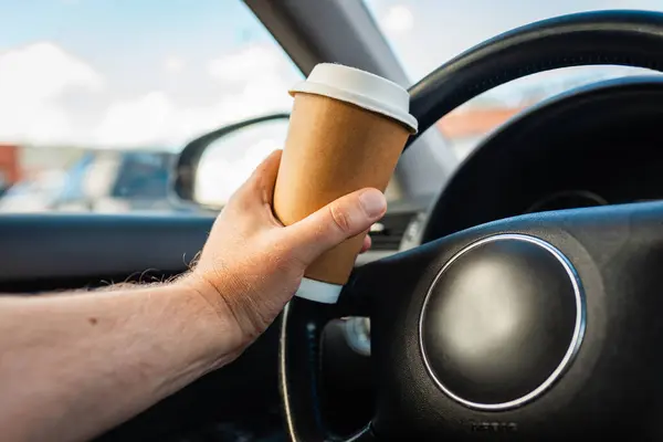 Transportation and vehicle traffic jam concept.A person drinking paper cup hot coffee in hand while driving in a car in the traffic jam morning.