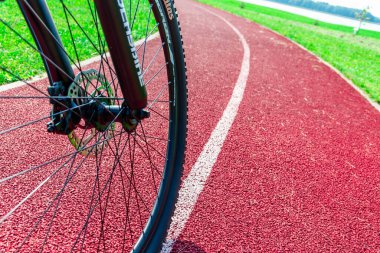 Yolda bir bisikletçi var. Bisikletli biri, kırmızı bir arka planda yukarıdan bisiklete biniyor. Yakından. Telsiai, Litvanya. 09-13-2023..