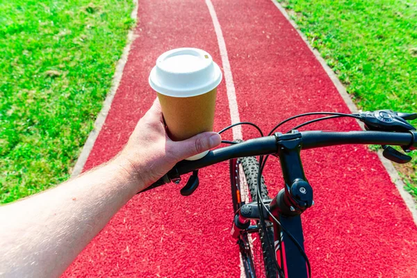 Cup of hot coffee in hands of a bicycle commuter. A minute of respite.Going to work by bike, active sport lifestyle concept.