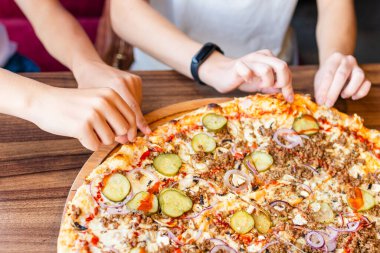 Pizzacıda bir araya gelen iki genç, lezzetli İtalyan yemeklerini paylaşırken eğleniyor, çeşitli meslekdaşlar ya da arkadaşlar pizza dilimlerini barda yiyor. Yaklaş, seçici odaklan..