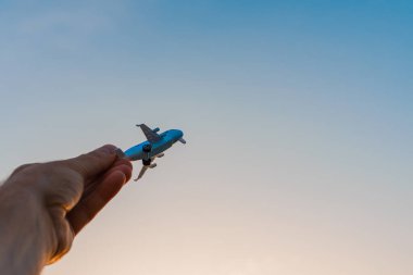 Oyuncak uçak tutan ve hayalleri olan bir adamın elleri pilot olmak ister. Arkaplanda bulanık bulutlar, mavi gökyüzü..