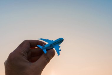 Oyuncak uçak tutan ve hayalleri olan bir adamın elleri pilot olmak ister. Arkaplanda bulanık bulutlar, mavi gökyüzü..