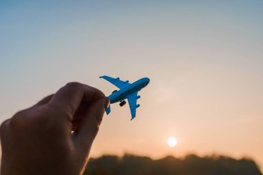 Oyuncak uçak tutan ve hayalleri olan bir adamın elleri pilot olmak ister. Arkaplanda bulanık bulutlar, mavi gökyüzü..