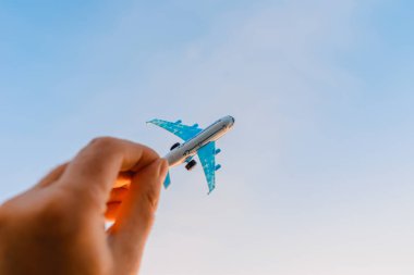 Oyuncak uçak tutan ve hayalleri olan bir adamın elleri pilot olmak ister. Arkaplanda bulanık bulutlar, mavi gökyüzü..