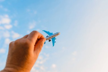 Bir adamın elindeki oyuncak uçak gökyüzünün arka planında bulutlu bir şekilde. Elinde uçak tutan ve bulutlu gün batımı üzerinde uçan adam mavi gökyüzü arka planı. Seyahat motivasyon konsepti..
