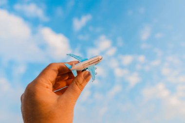 Oyuncak uçak tutan ve hayalleri olan bir adamın elleri pilot olmak ister. Arkaplanda bulanık bulutlar, mavi gökyüzü..