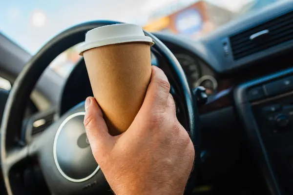 Busy male with a cup of coffee in the car behind the wheel.Transportation and vehicle traffic jam concept.