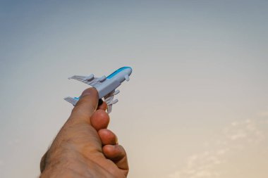 Oyuncak uçak tutan ve hayalleri olan bir adamın elleri pilot olmak ister. Arkaplanda bulanık bulutlar, mavi gökyüzü..