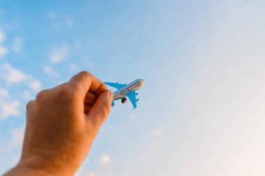 Oyuncak uçak tutan ve hayalleri olan bir adamın elleri pilot olmak ister. Arkaplanda bulanık bulutlar, mavi gökyüzü..