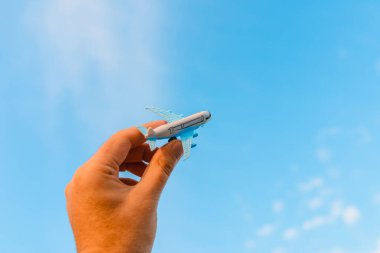 Oyuncak uçak tutan ve hayalleri olan bir adamın elleri pilot olmak ister. Arkaplanda bulanık bulutlar, mavi gökyüzü..