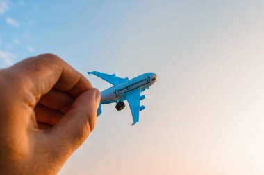 Oyuncak uçak tutan ve hayalleri olan bir adamın elleri pilot olmak ister. Arkaplanda bulanık bulutlar, mavi gökyüzü..