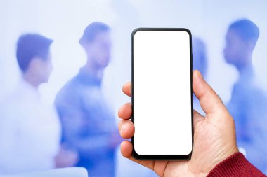 Beyaz ekranlı, modern akıllı telefonu elinde tutan bir erkek. İş adamları sokakta yürüyor. Mesaj ya da içerik için hazırlar. Cep telefonlu bir adam..