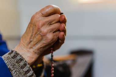 Yaşlı kadın duası, Rosary. Kadın elleri dua ediyor, Rosary boncukları tutuyor. Hristiyan kadın haç haçı tutuyor, kilisede Tanrı 'ya dua ediyor. Seçici odaklanma. Hristiyanlık kavramı. İnsanlar inanç ve uygulama..