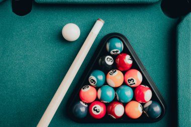 Yeşil elbiseli bir bilardo oyunu. İçinde numaralar, bilardo topu ve bilardo masasının üzerinde üçgen olan çok renkli bilardo topları. Bilardo toplarını yakın çekim..