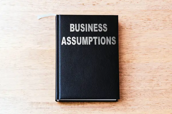 Business assumptions black business book on the office wooden table.Closeup,selective focus.