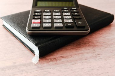 İş stratejisi kavramı. Bir işletme kara kitabı, hesap makinesi ofis tahtasının üzerine uzanıyor. Yakın plan, seçici odaklanma..