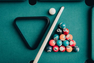 Yeşil elbiseli bir bilardo oyunu. İçinde numaralar, bilardo topu ve bilardo masasının üzerinde üçgen olan çok renkli bilardo topları. Bilardo toplarını yakın çekim..