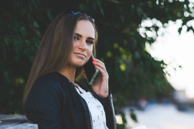 Halka açık parkta cep telefonuyla konuşan güzel bir kadın..