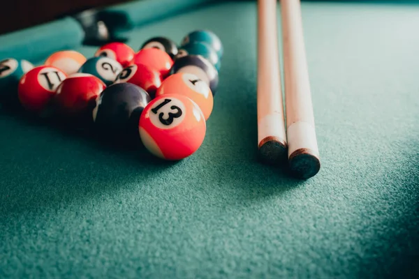 Sports game of billiards on a green cloth.Multi colored billiard balls in the form of a triangle with numbers,a two cues ball and a triangle on a pool table. billiard balls closeup.Toned.