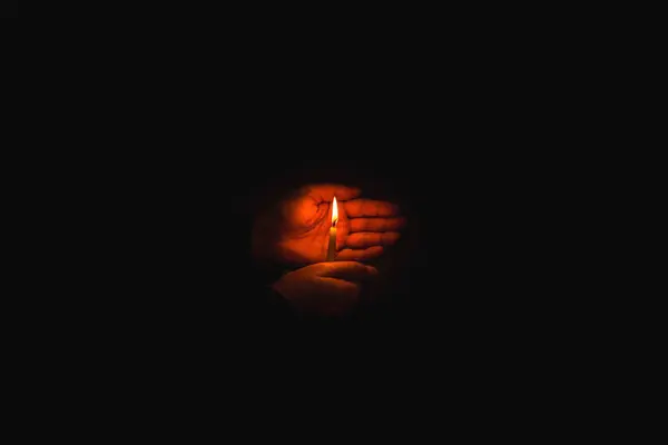 Candle in the hands.Man hands holding a burning candle on dark background.Religious concept.Copy space.