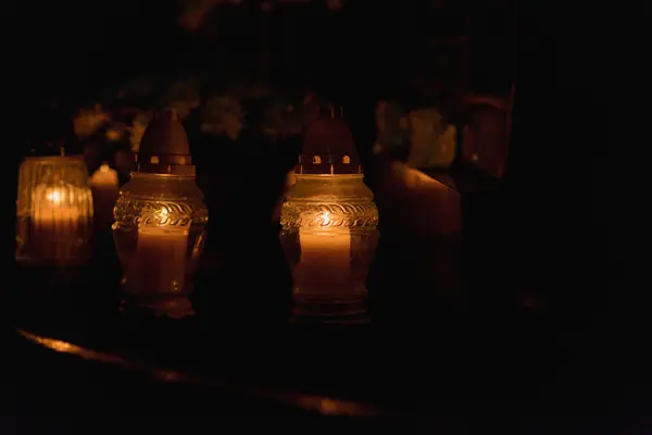 Candles Burning at Night.White Candles Burning in the Dark with lights glow.Focus on candles in foreground.