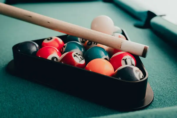 Sports game of billiards on a green cloth.Multi colored billiard balls in the form of a triangle with numbers,a cue ball and a triangle on a pool table. billiard balls closeup.Toned.