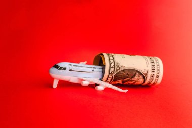 Toy airplane, twisted dollar bill, red surface.Copy space.