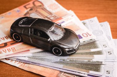 Farklı euro banknotları üzerinde oyuncak bir araba. Araba satın alma, kiralama, hizmet, onarım ve sigorta masrafları. Masraflar için planlama.