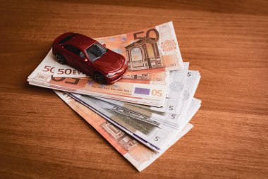 Farklı euro banknotları üzerinde oyuncak bir araba. Araba satın alma, kiralama, hizmet, onarım ve sigorta masrafları. Masraflar için planlama.