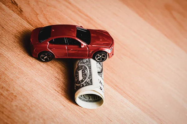 Concept of insurance, credit and car purchases,car loan.Auto dealership and rental, new car buy. toy car dollar bill on a table,toned image.