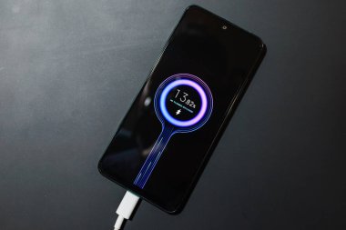 Telefon şarjı. Dizüstü bilgisayardaki cep telefonu şarjı akıllı şarj aletinden şarj oluyor. Modern teknoloji, taşınabilir hızlı şarj cihazı..