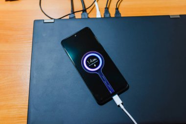 Telefon şarjı. Dizüstü bilgisayardaki cep telefonu şarjı akıllı şarj aletinden şarj oluyor. Modern teknoloji, taşınabilir hızlı şarj cihazı..
