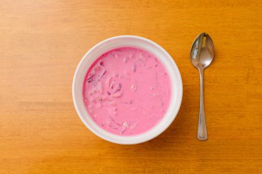 Masanın üzerinde bir kase pembe soğuk çorba. Üst görünüm.