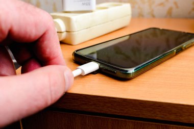 İnsanlar evdeki akıllı bir telefona şarj aleti takıyorlar..