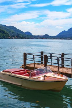 Lugano Gölü 'nün güzel manzarası. İsviçre' nin Morcote köyündeki kıyıya demirlemiş lüks sürat teknesi. Güneşli bir yaz gününde arka planda güzel İsviçre manzarası ve Alpler.