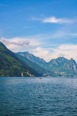 Güneşli bir yaz gününde arka planda yeşil İsviçre Alpleri ile Lugano Gölü boyunca seyreden sürat teknesinin güzel manzarası. Ticino Kantonu, İsviçre.