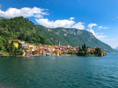 Varenna, Lombardy, İtalya 'da Como Gölü kıyısındaki binaların ve kilisenin manzarası güneşli bir yaz gününde. 