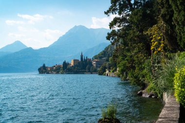 Como Gölü 'nün geniş panoramik manzarası ve Villa Monastero' nun İtalya 'nın Lecco ilindeki muhteşem göl bahçesi boyunca yürüme yolundan görünen geleneksel Varenna köyü..