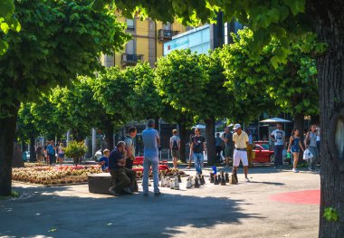 İsviçreli yerliler, İsviçre 'nin Lugano, Riforma Meydanı' ndaki açık hava satrancı oynamak için öğle yürüyüşlerine ara verdiler..