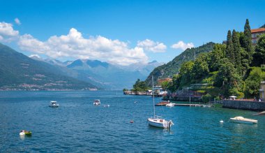 Lombardy, İtalya 'da büyüleyici bir balıkçı kasabası olan Varenna kıyısı yakınlarındaki balıkçı tekneleriyle Como Gölü' nün büyüleyici manzarası. Güneşli bir yaz gününde, arka planda yemyeşil Avrupa Alpleri var..