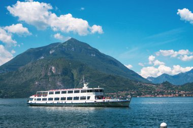 Lombardy, İtalya 'nın büyüleyici bir köyü olan Varenna kıyısı yakınlarındaki Como Gölü' nde güneşli bir yaz günü, arka planda yeşil Alpler ile birlikte giden feribot feribotu.. 