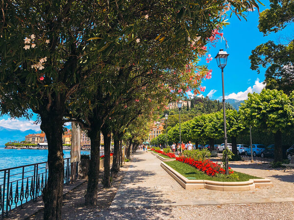 People enjoying the walk in landscaped fragrant park in Bellagio, one of the most beautiful towns in Italy, with picturesque shoreline and Alpine views.