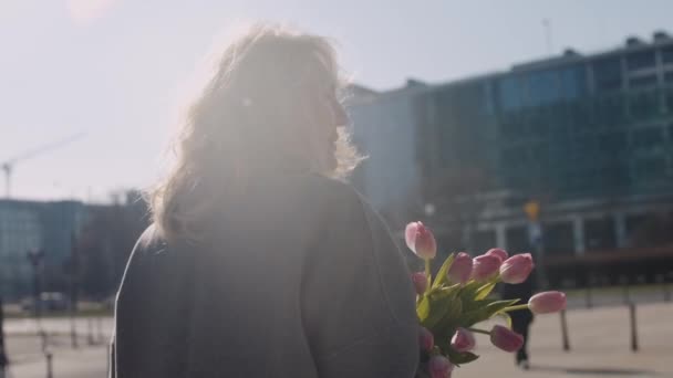 Старша Кавказька Елегантна Жінка Йде Вулиці Тримає Букет Рожевих Тюльпанів — стокове відео