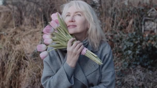 Elegancka Dojrzała Kobieta Kwiatami Ławce Biała Dorosła Kobieta Bukietem Różowych — Wideo stockowe