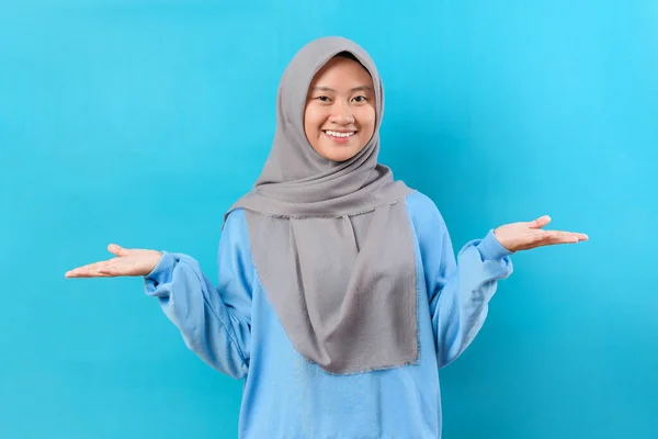 幸せなインドネシアのイスラム教徒の女性の笑顔を開いて手のひらを保持します 魅力的なインドネシアの楽しいです陽気な女の子を保持上の2つのヤシのコピー空の空白のスペース提供隔離された上の青の色の背景 — ストック写真