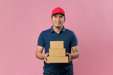 Kırmızı şapkalı mutlu teslimatçı elinde pembe arka planda izole edilmiş bir posta kutusu tutuyor..
