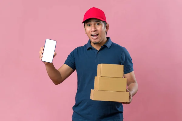 Kırmızı Başlıklı Telefon Ekranını Gösteren Mutlu Teslimatçı Pembe Arka Planda — Stok fotoğraf